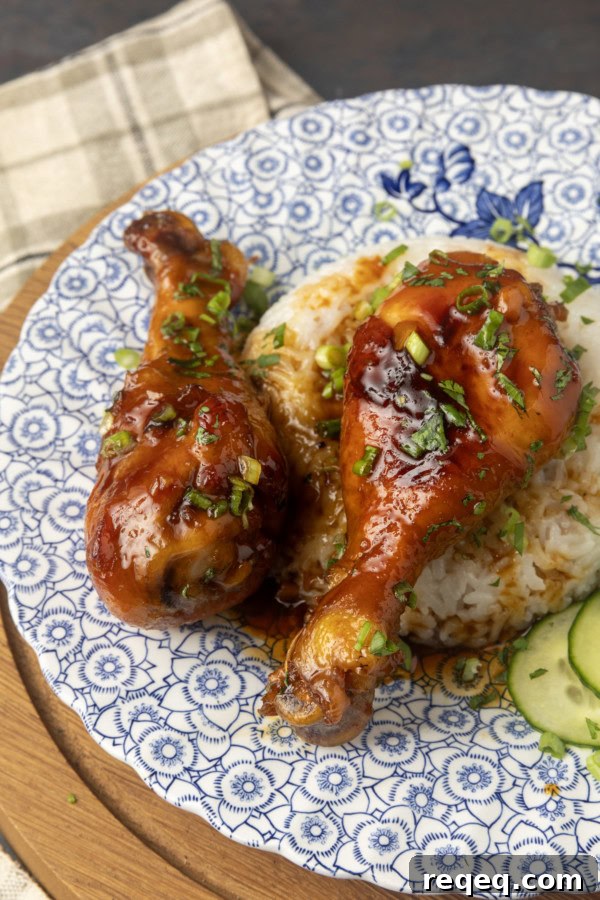baked honey garlic chicken on rice with cucumbers on a blue and white plate