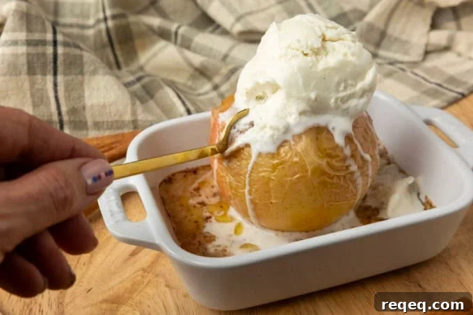 old fashioned baked apple with vanilla ice cream and a hand holding a spoon