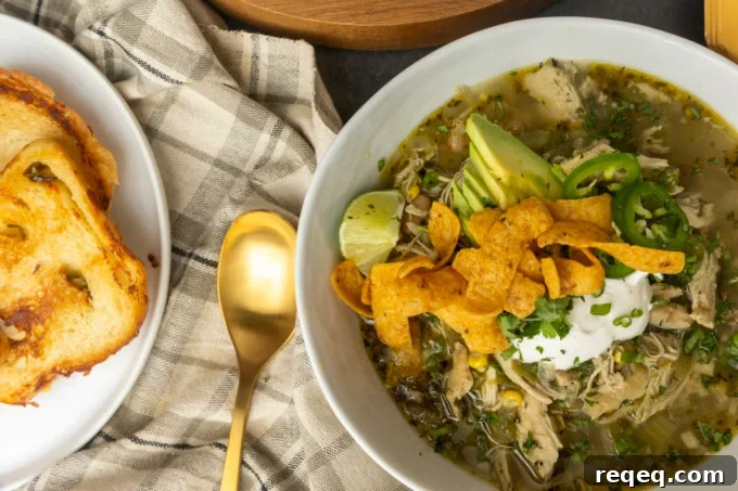 Slow-Cooker White Bean Chicken Chili Recipe for Comforting Weeknight Meals 2 white bean chicken chili in a bowl with avocados, jalapenos, sour cream, cilantro, fritos, and lime wedges