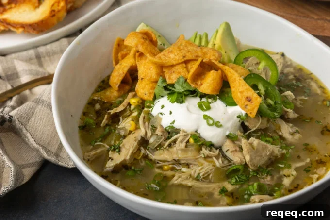 Slow-Cooker White Bean Chicken Chili Recipe for Comforting Weeknight Meals 3 white bean chicken chili in a bowl with avocados, jalapenos, sour cream, cilantro, fritos, and lime wedges