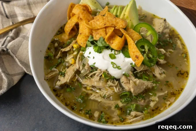 Slow-Cooker White Bean Chicken Chili Recipe for Comforting Weeknight Meals 6 white bean chicken chili in a bowl with avocados, jalapenos, sour cream, cilantro, fritos, and lime wedges