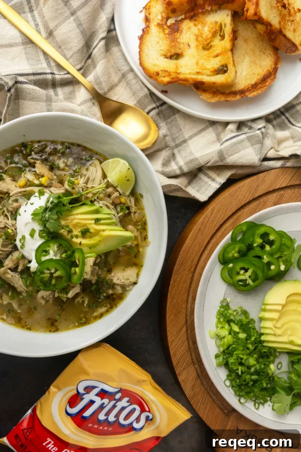 Slow-Cooker White Bean Chicken Chili Recipe for Comforting Weeknight Meals 7 white bean chicken chili in a bowl with avocados, jalapenos, sour cream, cilantro, fritos, and lime wedges