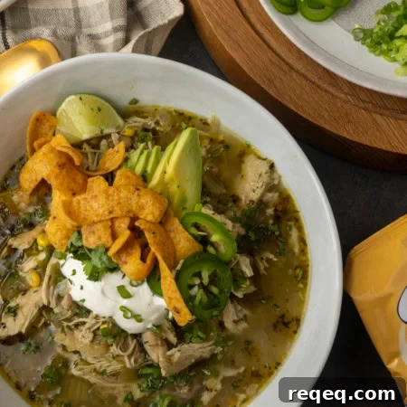 Slow-Cooker White Bean Chicken Chili Recipe for Comforting Weeknight Meals 8 white bean chicken chili in a bowl with avocados, jalapenos, sour cream, cilantro, fritos, and lime wedges
